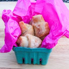 a blue basket filled with pastries on top of a wooden table