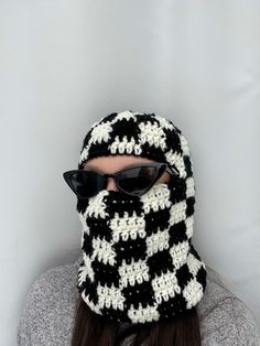 a woman wearing a black and white crocheted hat with sunglasses on her head