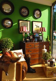 a living room with green walls and pictures on the wall, furniture in front of it