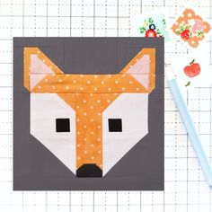 a piece of fabric with an orange and white fox on it next to a pencil