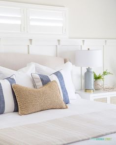 a bed with white sheets and blue pillows