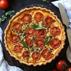 a tomato and basil quiche on a wooden cutting board with tomatoes around the edges