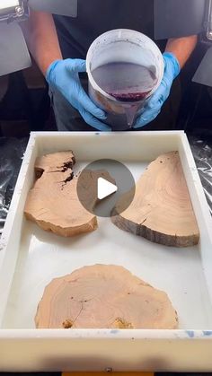 a person in blue gloves is holding a cup and some slices of wood on a tray