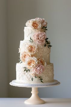 a three tiered wedding cake with pink flowers on the top and bottom, sitting on a white pedestal