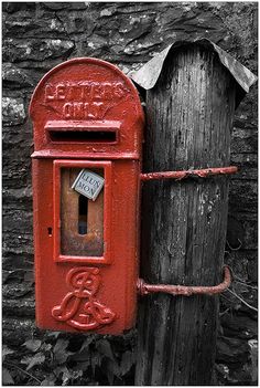 an old fashioned red mailbox attached to a wooden post