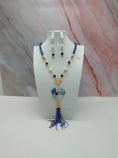 "Handmade and designed by me-one of a kind necklace set-blue seed bead crocheted rope necklace-24\"-6\" long focal with a banded agate heart pendant bead and a 4\" long seed bead tassel-lapis lazuli beads-glass beads-metal beads-2 1/4\" long matching dangle earrings-gold tone toggle clasp in front-gold tone findings. This unique gemstone necklace set would be a beautiful addition to your jewelry wardrobe! The necklace is easy on because of the toggle clasp in the front." Blue Necklace With Colorful Dangle Beads, Elegant Blue Wire Wrapped Beaded Necklaces, Elegant Blue Wire Wrapped Beaded Necklace, Blue Wire Wrapped Necklaces With Round Beads, Blue Beaded Lariat Necklace With Beaded Chain, Blue Lariat Beaded Necklace For Gift, Blue Dangle Necklaces With Gemstone Beads, Blue Dangle Gemstone Beads Necklace, Blue Gemstone Beads Dangle Necklaces