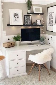 a white desk topped with a computer monitor and a laptop next to a wall filled with pictures