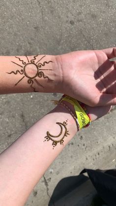 two people holding hands with tattoos on their arms and the sun and moon drawn on them