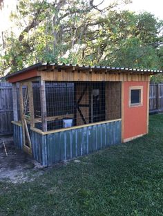 a small chicken coop in the yard with a fence around it's back door