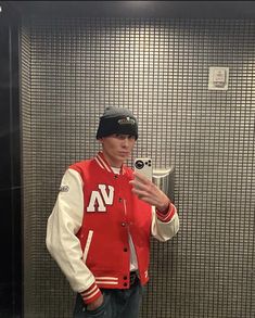 a man standing in front of a mirror wearing a red and white jacket with the letter n on it