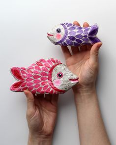 two handmade fish made out of yarn sitting next to each other in front of a white background