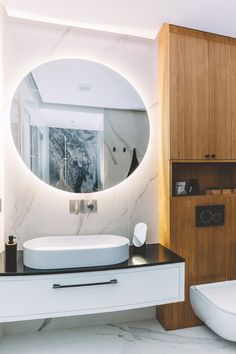 a bathroom with a round mirror on the wall and marble counter top in front of it