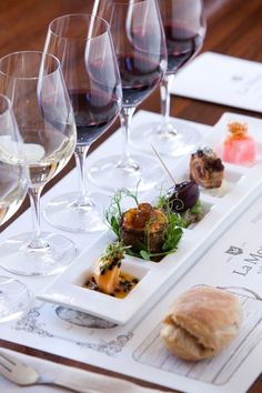 three glasses of wine are sitting on a table with food and garnishes