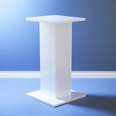 a white pedestal stands against a blue wall