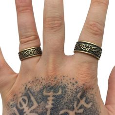 a person's hand with two rings on it and tattoos on their fingers,