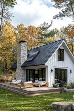 a white house with a black roof in the woods