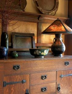 an old dresser with two vases and a lamp on top, in front of a mirror