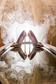 two pairs of high heeled shoes sitting on top of a glass table in front of a window