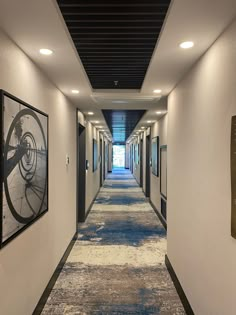 a long hallway with pictures on the wall and carpeted flooring in an office building