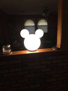 a lighted mickey mouse head sitting on top of a brick wall next to a window