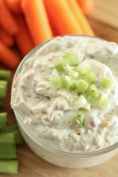 celery sticks and carrots next to a bowl of ranch dip on a cutting board