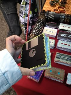 a person holding up a cd case made out of paper on top of a table