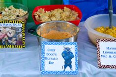 several bowls of food on a table with name tags and place cards for guests to eat