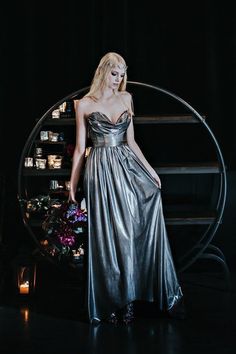 a woman in a silver dress standing next to a round object