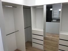 an empty white closet with wooden floors and drawers