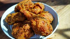 some fried food in a white bowl on a wooden table