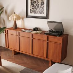 a record player sitting on top of a wooden cabinet next to a plant in a living room