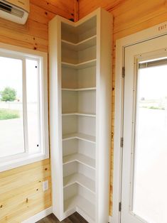 an empty room with wooden walls and white shelves