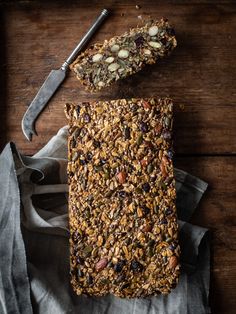 granola bars with nuts and seeds are on a napkin next to a knife, fork and spoon