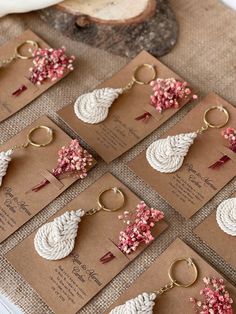 wedding favors are arranged on brown cards with pink and white flowers in the shape of leaves