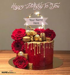 a red and gold birthday cake with chocolates, roses and candies on top