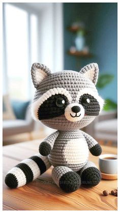 a crocheted raccoon sitting on top of a wooden table