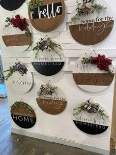 several wooden signs hanging from the side of a wall with wreaths and bows on them