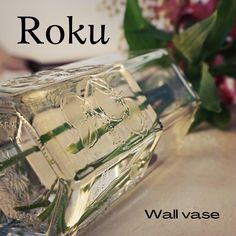 a glass vase with flowers in it sitting on a table next to the words rokuu