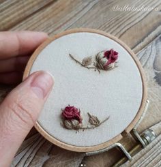 someone is stitching some flowers on a piece of fabric in the hoop with scissors