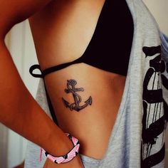 an anchor tattoo on the back of a woman's left side ribcage