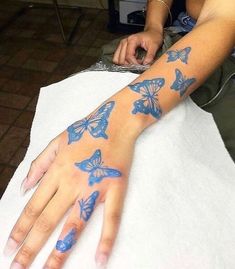 a woman with blue butterflies painted on her arm and hand is sitting at a table