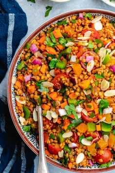 a bowl filled with lentils, carrots and other vegetables next to a spoon