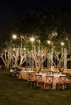 an outdoor dinner setup with lights strung from trees