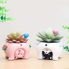 two ceramic animals with succulents on their heads are sitting next to each other