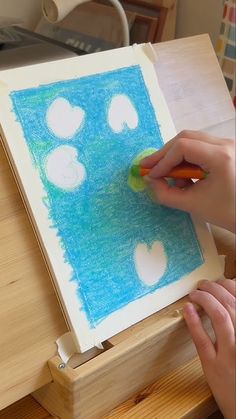 a person is drawing on a piece of paper with colored pencils and watercolor paints