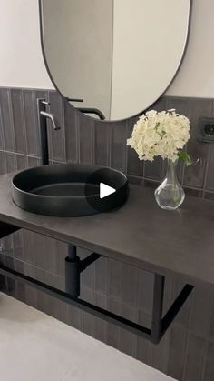 a bathroom with a sink, mirror and flowers on the counter top in front of it