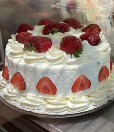 a white cake with strawberries on top in a display case