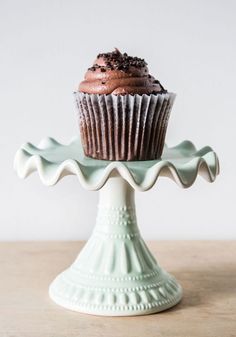 a chocolate cupcake sitting on top of a cake stand