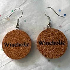 two wine cork earrings with the words wineholf written on them