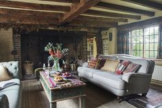 a living room filled with furniture and a fire place next to a brick wall covered in windows